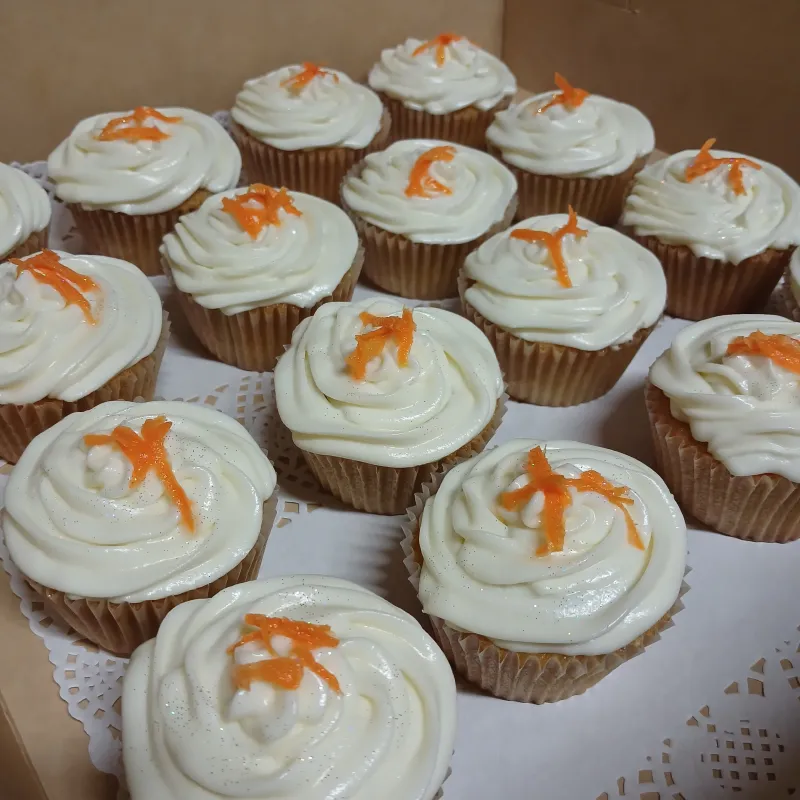 Carrot cupcakes with cream cheese frosting on top with candied carrots